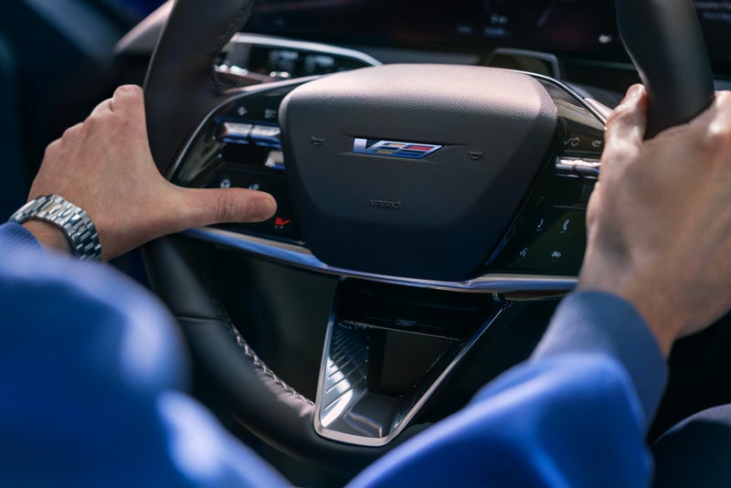 Close-up of a Man About to Press the V-Button on the 2026 OPTIQ-V Steering Wheel | Heritage Cadillac in Morrow GA