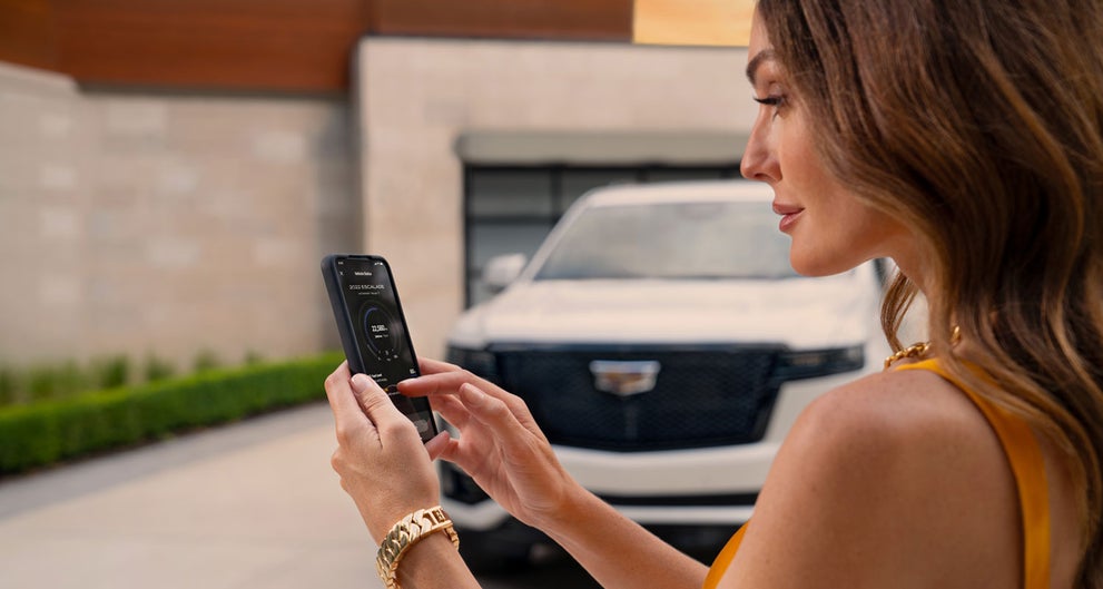 lady checking her mobile with a Cadillac vehicle background | Heritage Cadillac in Morrow GA